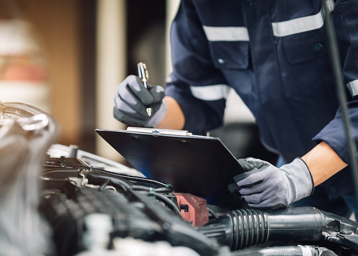 Maintenance technician inspecting the engine of a car in the garage.