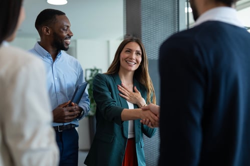 Smiling woman receiving handshake within a small group in professional environment