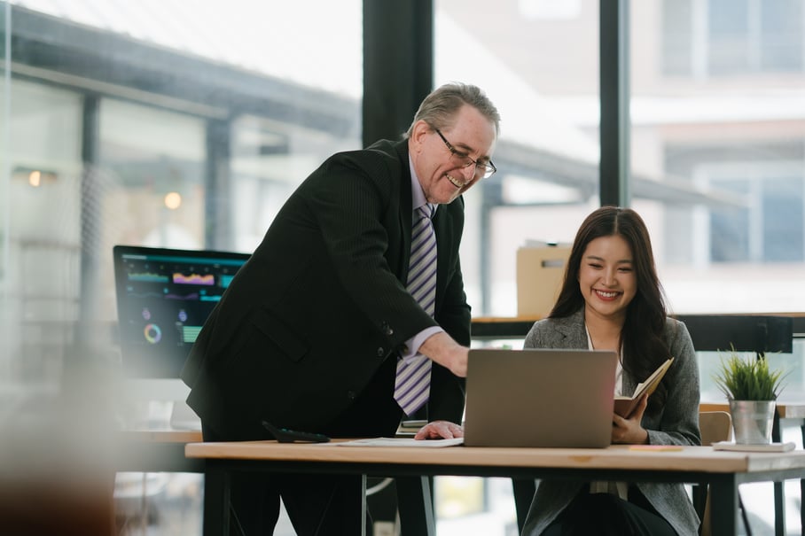 Two employees smiling as they look at a laptop together