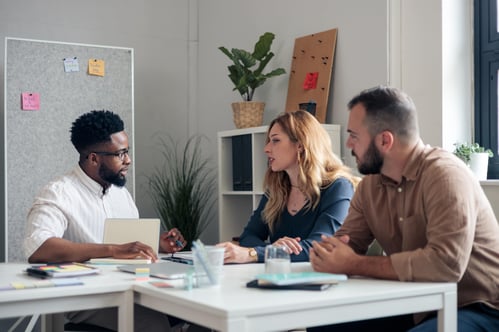Three coworkers talking at a table together