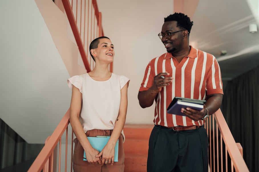 Two coworkers chatting as they go down the stairs