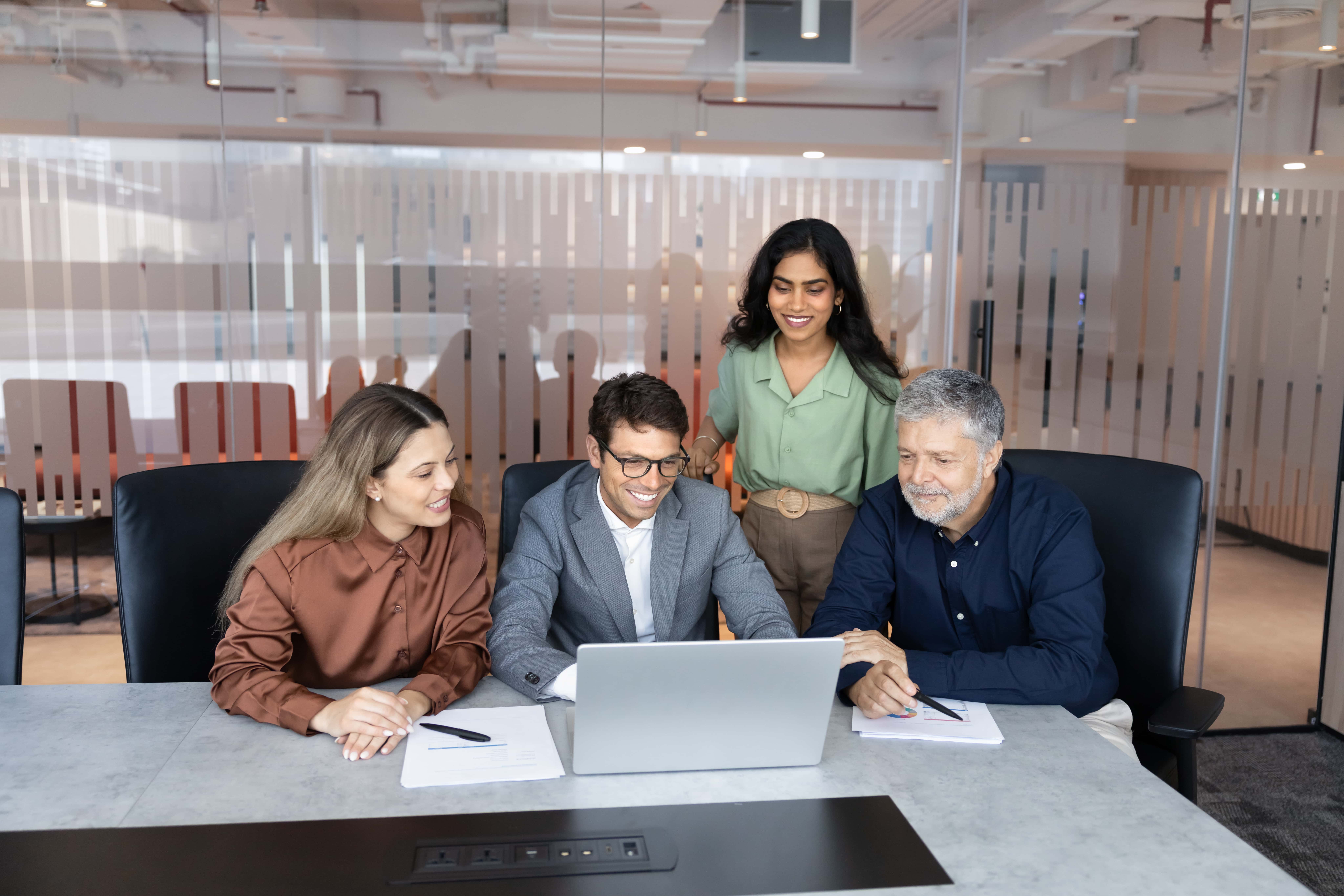 Group of workers around one laptop in meeting room