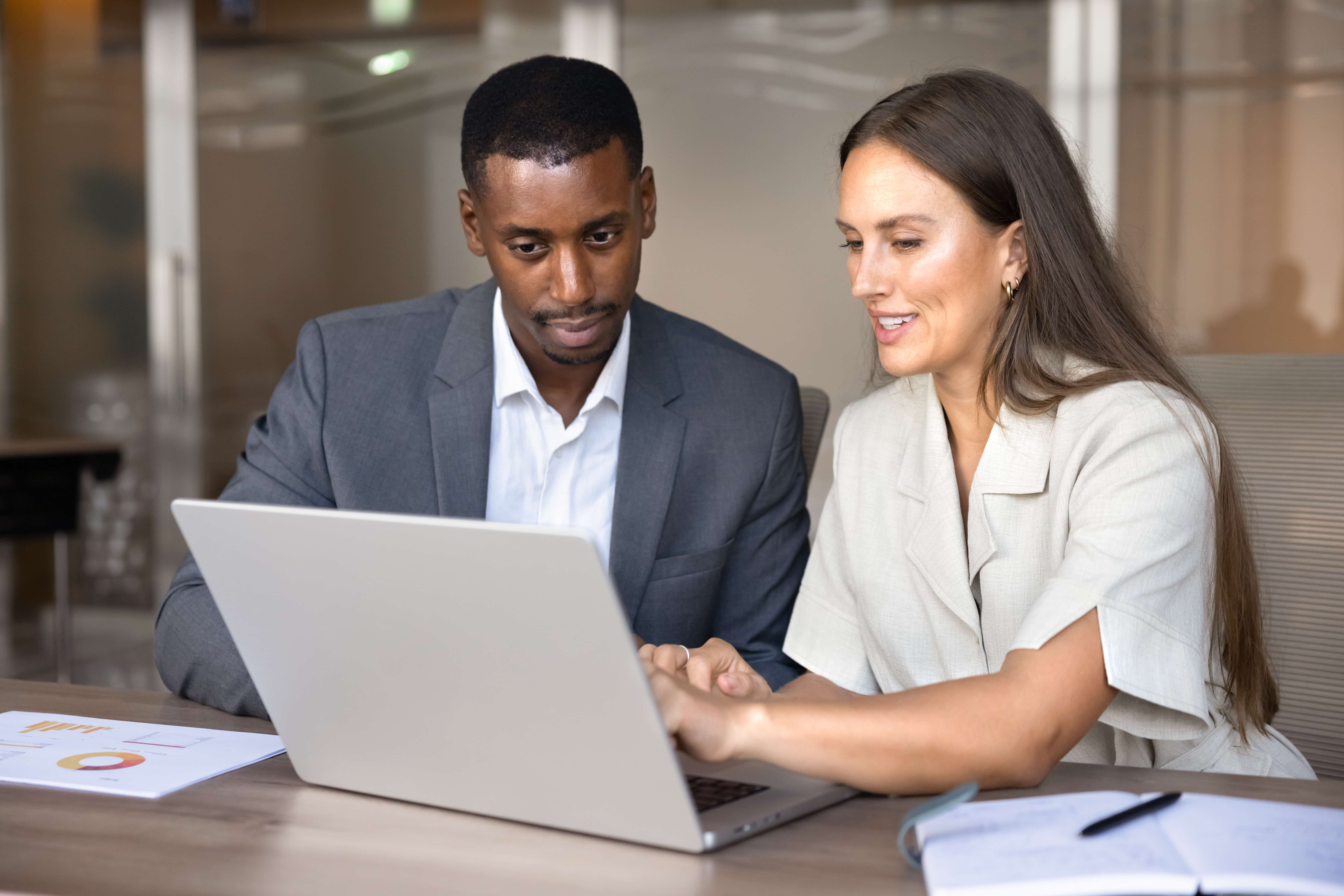 Two coworkers looking at a laptop together