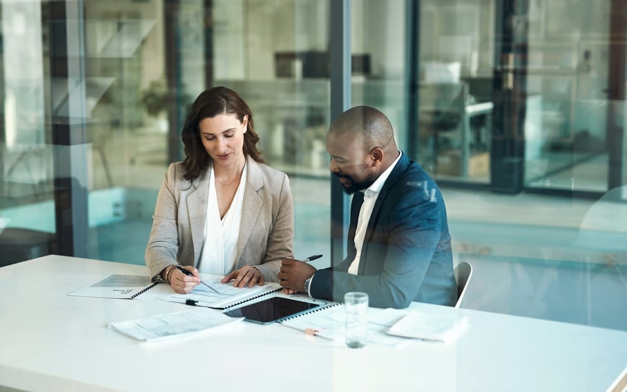 View through glass door of man and woman working together at table